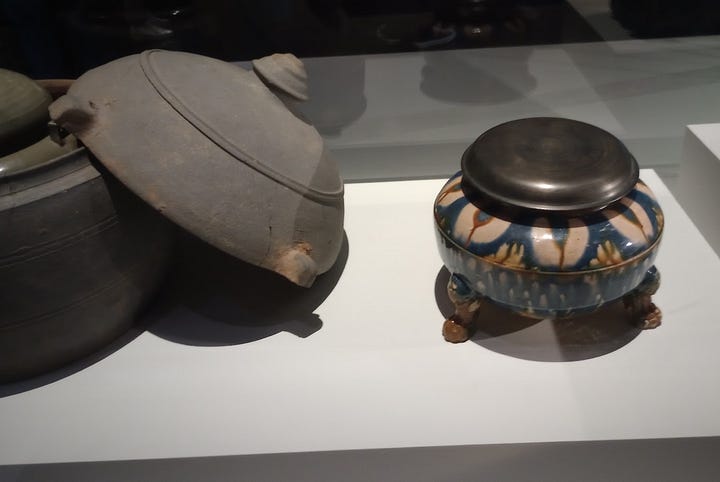 Left, gilded bronze box embossed with image of Buddha, right: lidded stone jar, and decorated earthenware jar