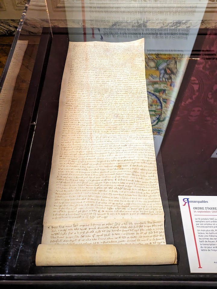 Two views of museum vitrines, with handwritten documents on scrolls of parchment. The one to the right is significantly longer and the unrolled section is thicker.