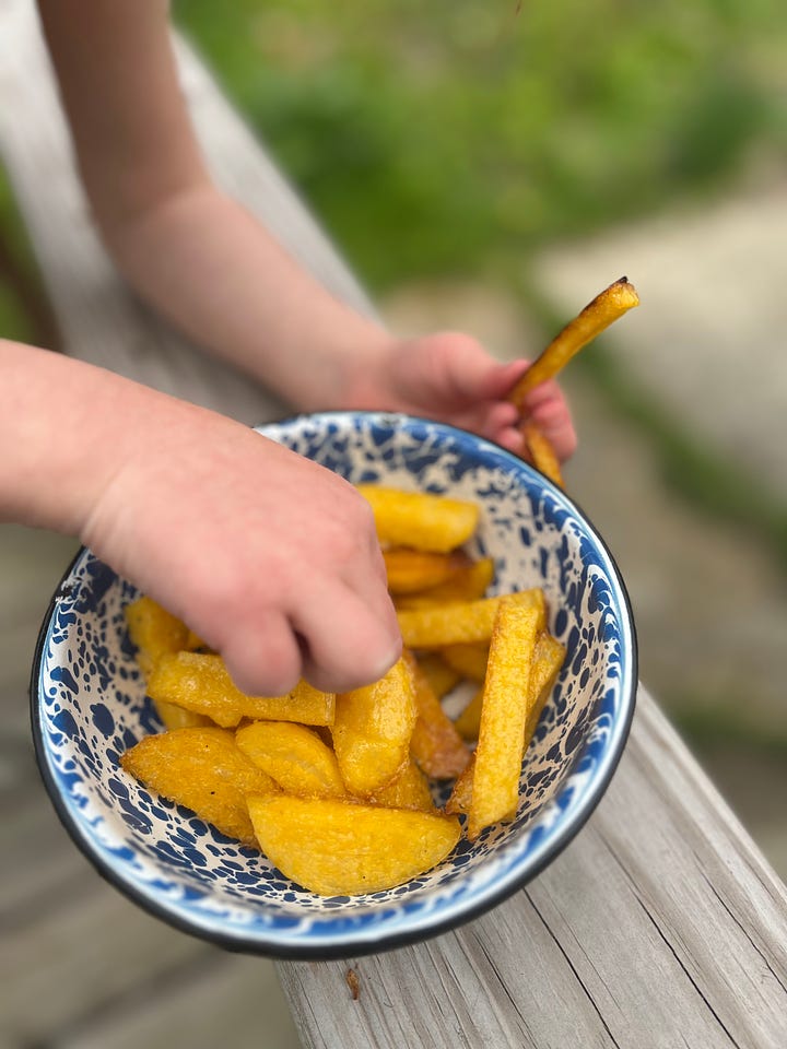 Pre-cooked polenta log and kid picking polenta fries out of blue speckled enamelware bowl