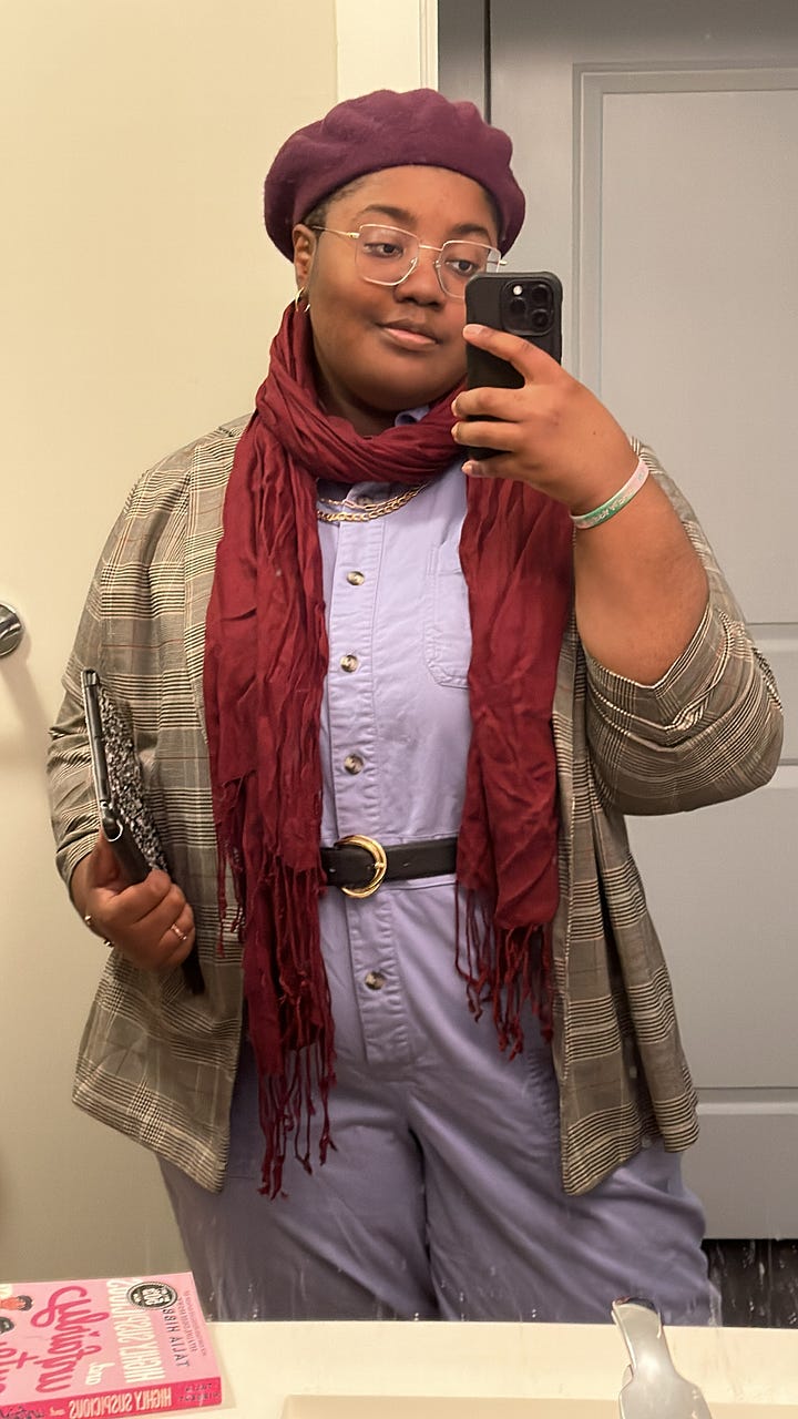 Image 1: Mirror photo of Ravynn in a lilac jumpsuit with a plaid blazer over it and a maroon scarf around her neck; image 2 is Ravynn in a maroon circle skirt and poet sleeve white blouse with a orange plaid cardigan over it and a maroon scarf around her neck and a purple beret on; image 3 is Ravynn in an Ironheart t-shirt, black blazer, and belted jeans; Image 4 is Ravynn in a feminist writers shirt with belted black jeans and a plaid blazer over top.