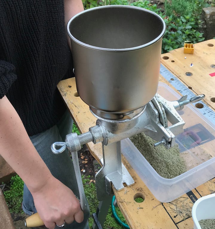 Metal grain grinder and handle attached to bench