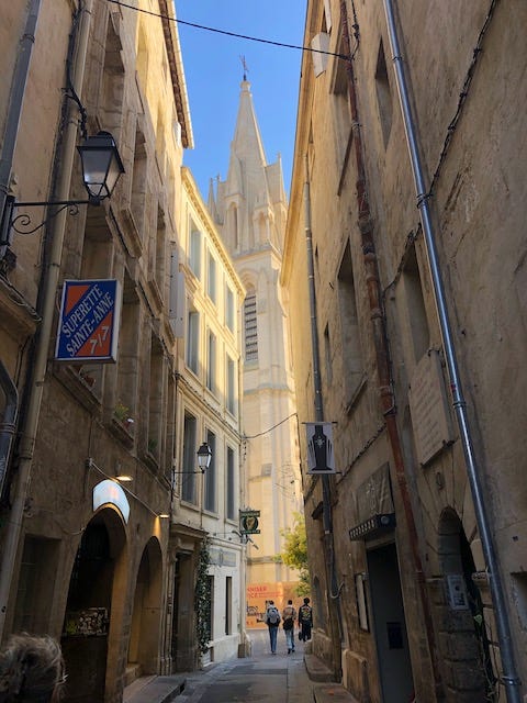 Four photos of medieval streets and buildings in Montpellier, France.