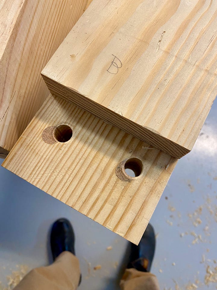 Drilling holes in the side of a workbench top, then filling holes with dowels and making new holes.