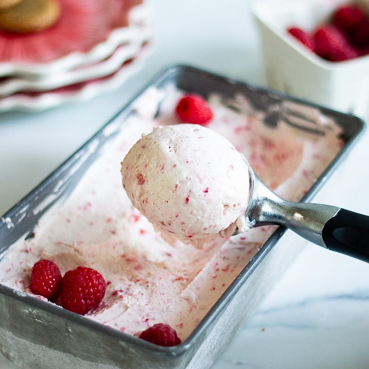 Raspberry ice cream in a white ceramic ramekin that was scooped from a loaf pan. 