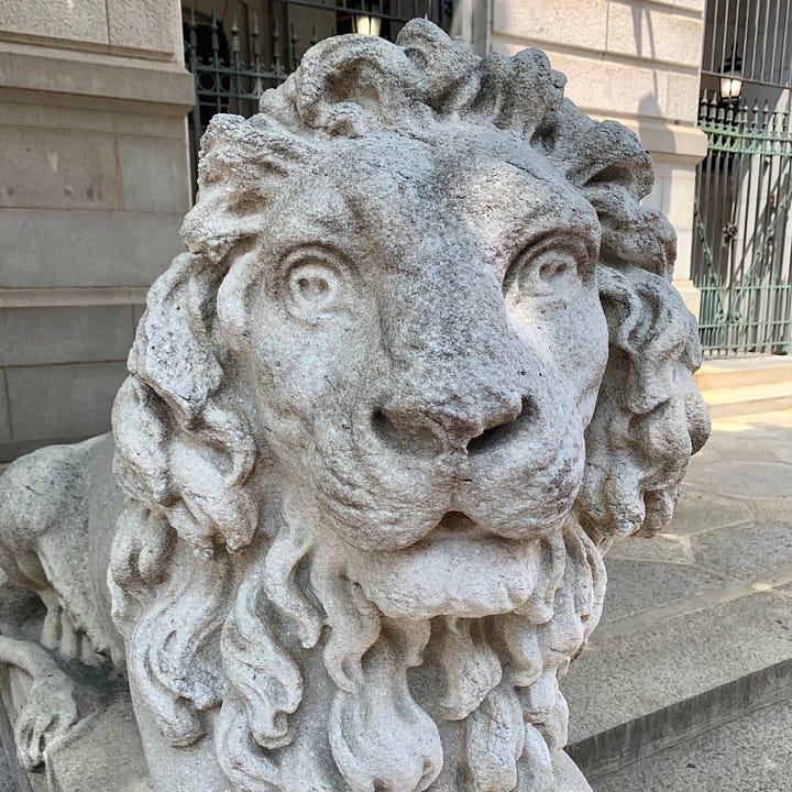 A street sign reading LEWIS and a statue of a lion