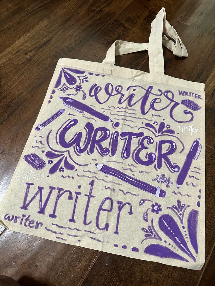 Left: a tote bag with "writer writer writer" hand lettered in purple acrylic paint and adorned with pens and pencils and other doodles; right: a tote which reads "storyteller" hand lettered in green acrylic paint and adorned with pencils, pens and two speech bubbles that read "once upon a time" and "the end"