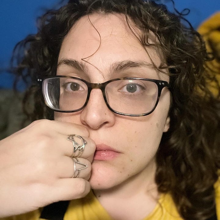 A Jewish woman in glasses showing off two rings on her right hand; a hand wearing a Magan David ring on the middle finger