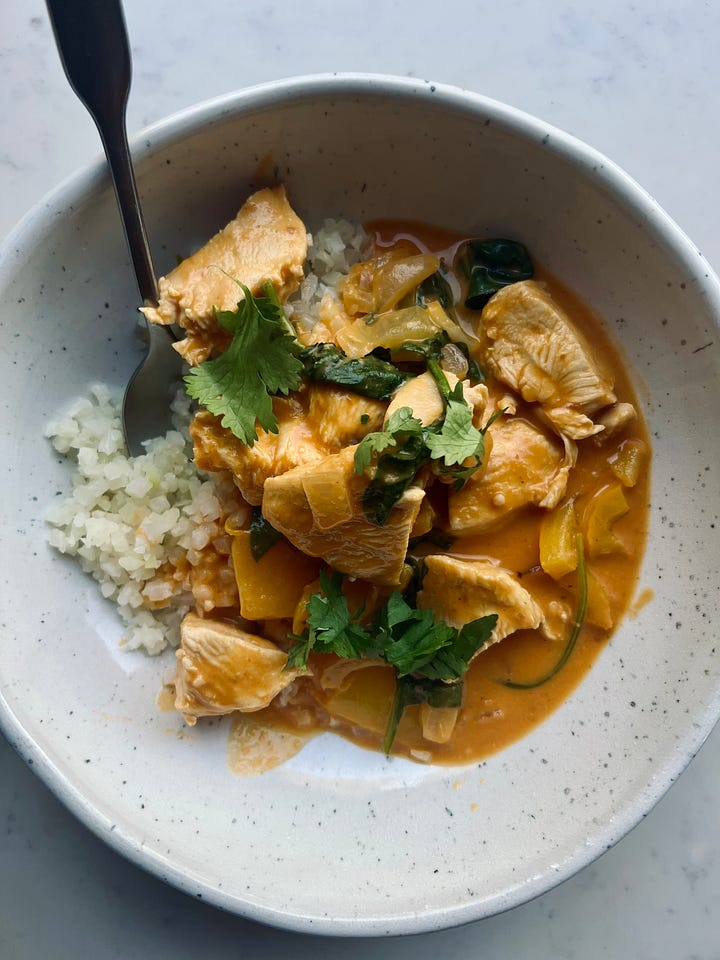 A pan of pumpkin curry next to a serving of pumpkin curry with cauliflower rice.