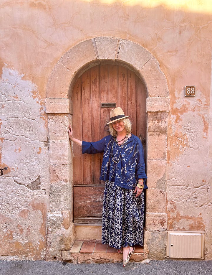 Karen Bussen stands next to a door in Provence, and scenes of a pretty street and pastel stone houses in Provence