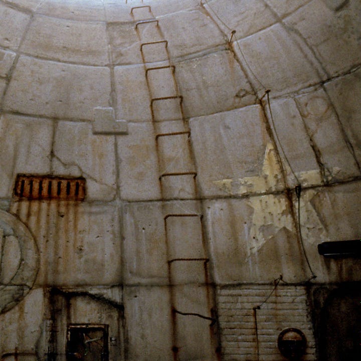 LEFT: Detail from LUMEN 5.1 featuring a man holding a large metal ring as he stands in the eye-shaped opening of an upward curving tunnel. RIGHT: Close detail from LUMEN 5.1 featuring curving textured wall. Rusty rebar forms a ladder up the curving slope. On the right, the paint of a yellow star chips and weathers. On the left a metal grate weeps lines of rust down the concrete.