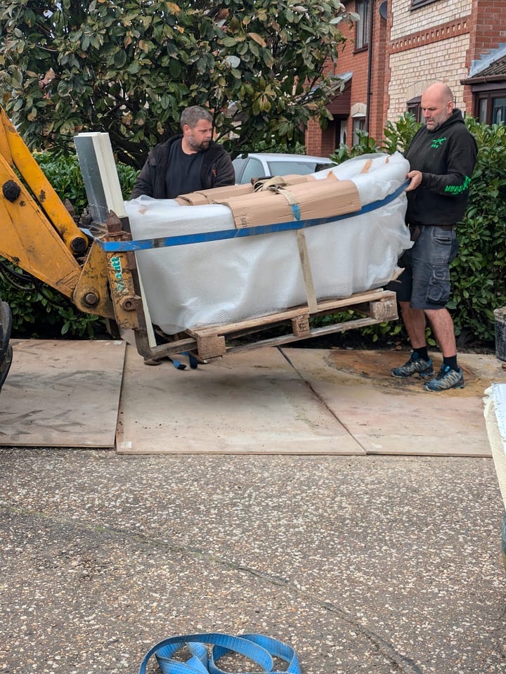 process of lifting a stone bath into an extension using a JCB telehandler