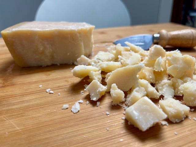 left to right: foil-wrapped bocconcino of parmigiano reggiano and a Parmareggio snack box, chunks of parmigiano at home on a wooden cutting board with a wooden handled cheese knife