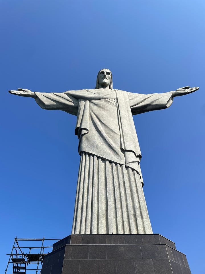 1. Christ the Redeemer from below. 2. The view of the ocean from atop a hill. 3. A trail marker painted on a rock (a yellow bootprint in a black arrow). 4. A close-up of a cool junction in a tree trunk.