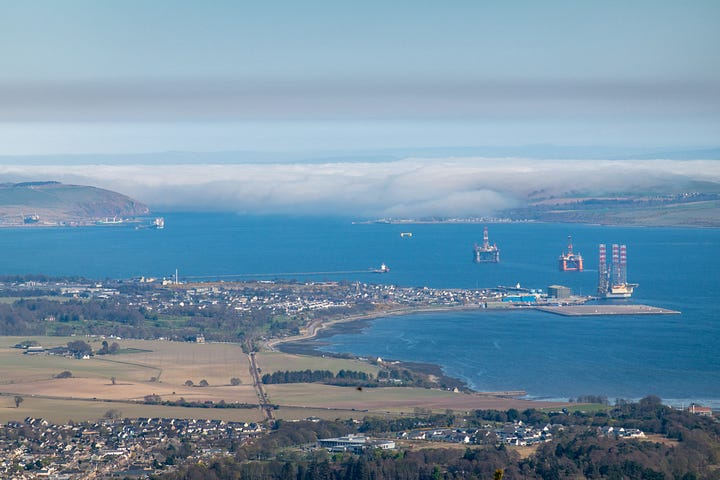 The Fyrish Monument above Alness with juniper and heather in the foreground; view of the Cromarty Firth with haar (sea fog) lapping over North and South Sutor and against the Black Isle © Felicity Martin