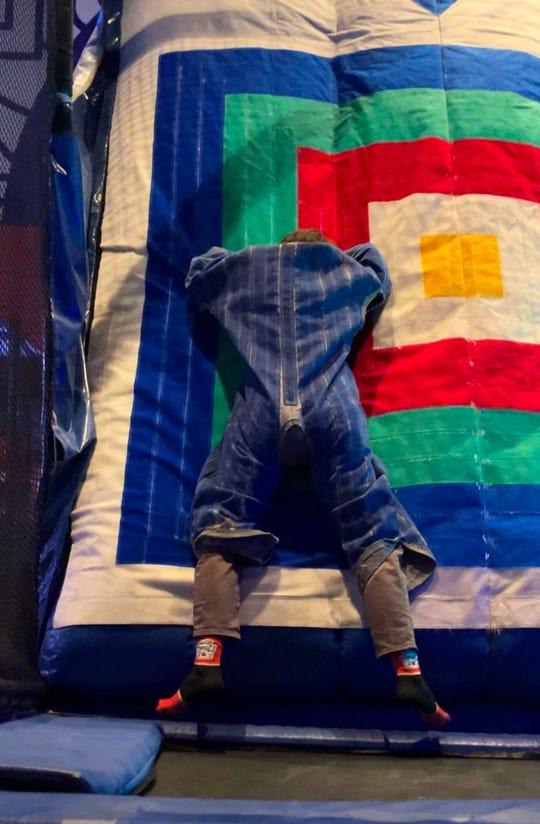 Two images of people in velcro suits stuck to a velcro wall