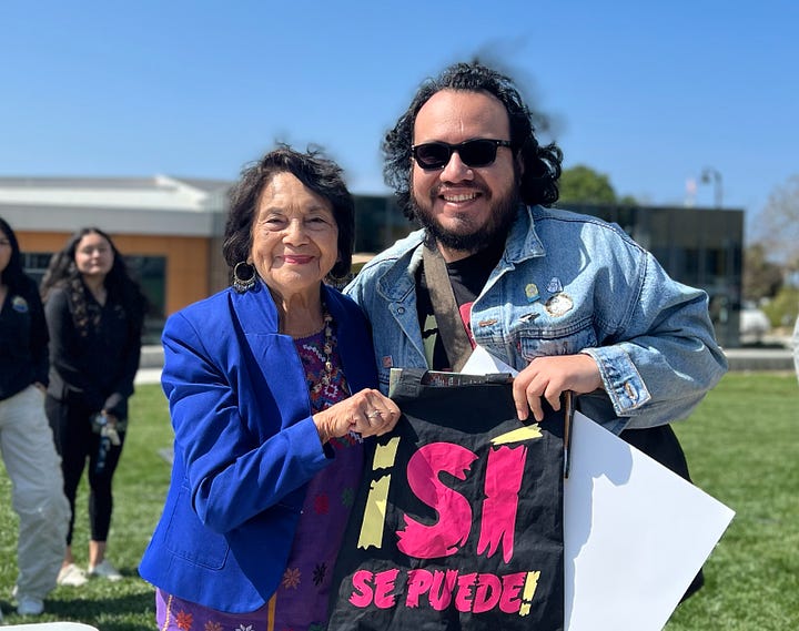 Dolores Huerta and Henry Barajas posing with a tote bag that reads ¡Sí Se Puede! at the 2023 Ventura College Diversity Fair. Ramon Jaurigue, and Cesar Chavez at the Inner City Center on December 4th, 1969.