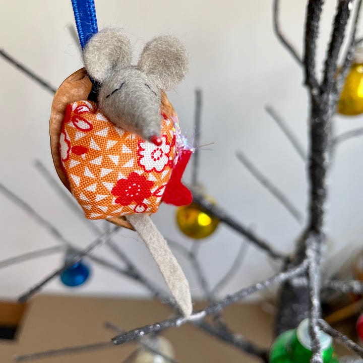 Christmas tree decorations made of tiny felt mice with quilts inside half walnut shells