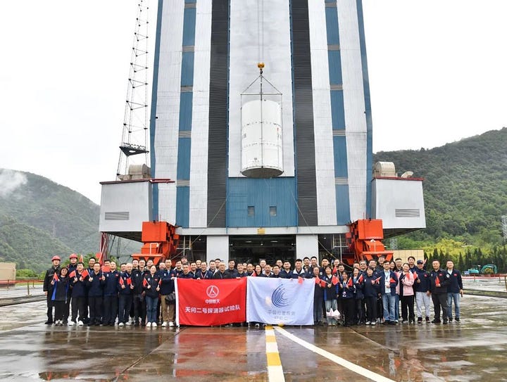 The Tianwen-2 probe, inside a protective casing, being lifted toward the top of the Long March 3B/E during launch preparations.
