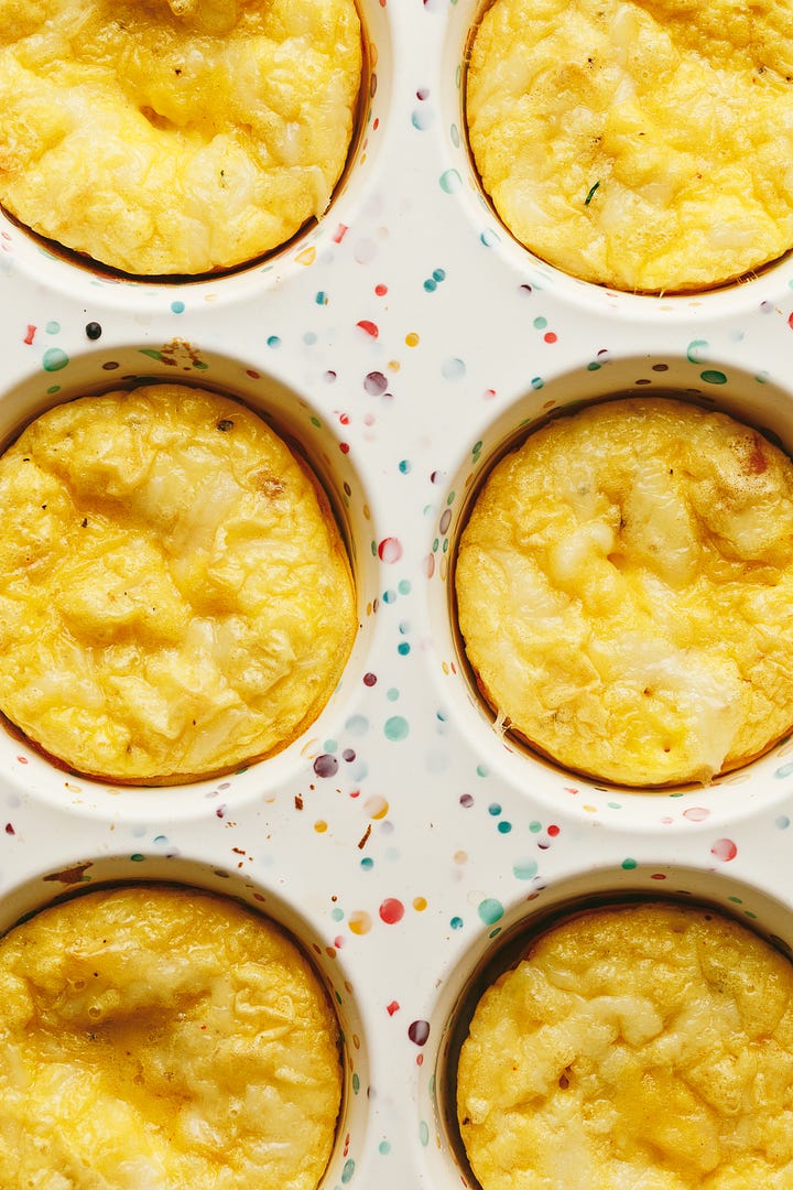 Egg bites in a silicone muffin pan; a bite taken out of one.