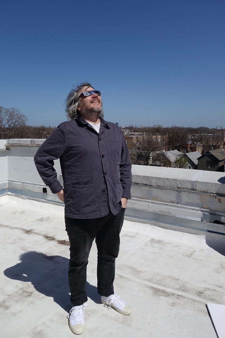 Jeff squints at the solar eclipse while wearing protective glasses; Jeff looks at the camera from a clawfoot bathtub; Jeff smiles with regular- and mini-size copies of the Wilco LP Cousin; Jeff feeds Icelandic horses