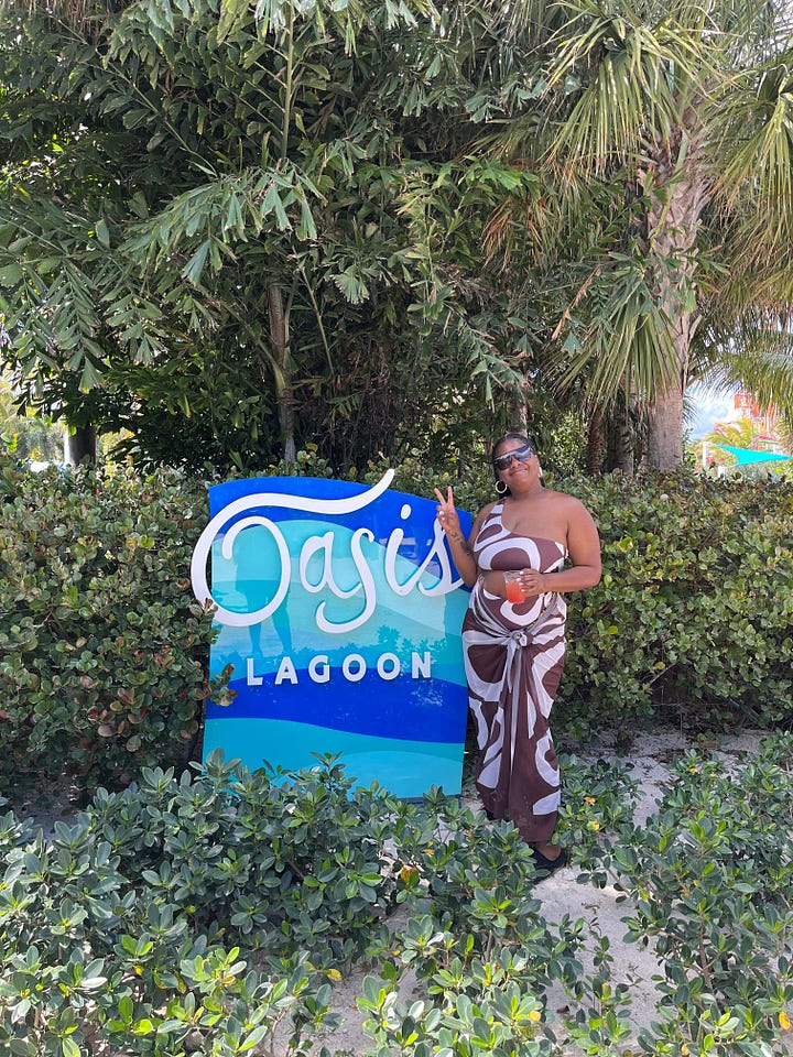 Left to right: Black woman sits a swim up bar with a yellow drink in her hand smiling. Black woman dressed in a purple and blue dress with a drink in her hand in front of crystal blue water. Black woman smiles in front of a beach in a white t-shirt and abstract matching short set. Black Woman stands in front of a blue and white sign that reads Oasis Lagoon, wearing a brown and white swim suit. 