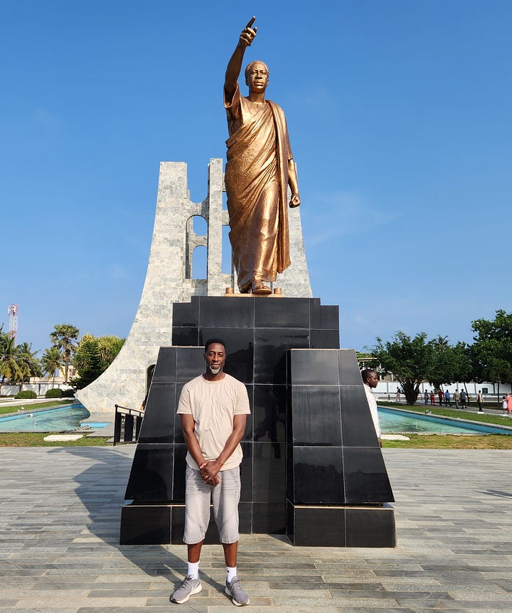 Nii Addy standing in front of a statue of Dr. Kwame Nkrumah. Nii Addy standing in front of a quote from Dr. Nkrumah, which reads "I am not African because I was born in Africa, but because Africa was born in me."