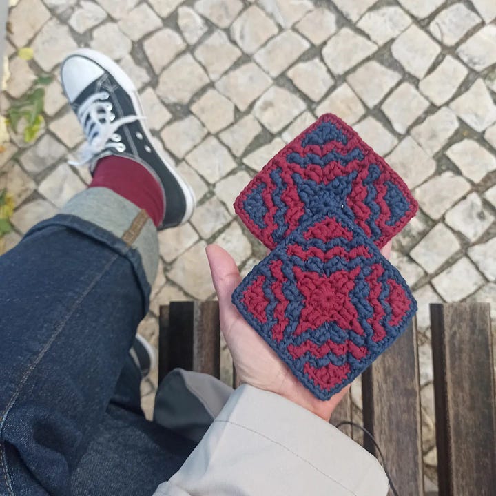 Overlay mosaic crochet squares made center-out, one with a flower design in white on denim blue; two in burgundy and navy-blue with a geometric design.