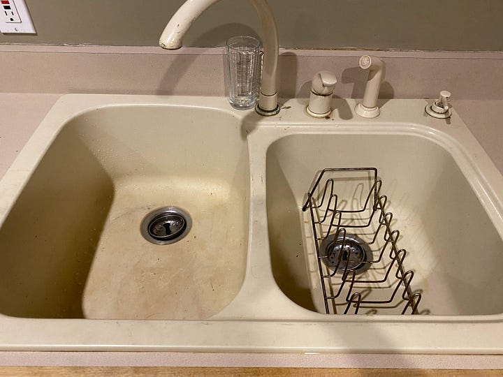 Worn out cabinets and stained kitchen sink.