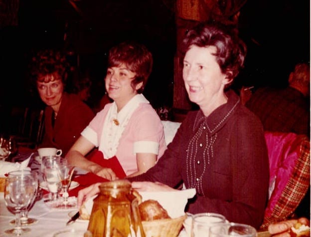 Four old photos. One shows a teenage girl sewing. She is slim, with reddish hair, and is wearing a striped tee shirt. The other three photos show eight women (one with gray hair, the rest dark haired) smiling and posing for their pictures around a very 1970s restaurant table, complete with amber colored candle holders.