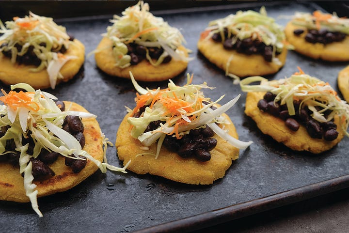 Collage of pupusa ingredients: shredded cheese, pupusa masa dough, black beans, curtido slaw, and sliced fried plantains on a gray table, plus a close up shot of the assembled pupusa with all the ingredients on top of the fried and flattened round pupusa dough