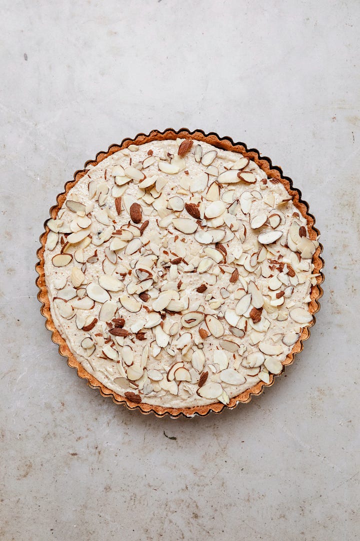 Vegan fresh cherry frangipane tart, including a pastry shell, cherry jam, cherries, almond frangipane and flaked almonds 