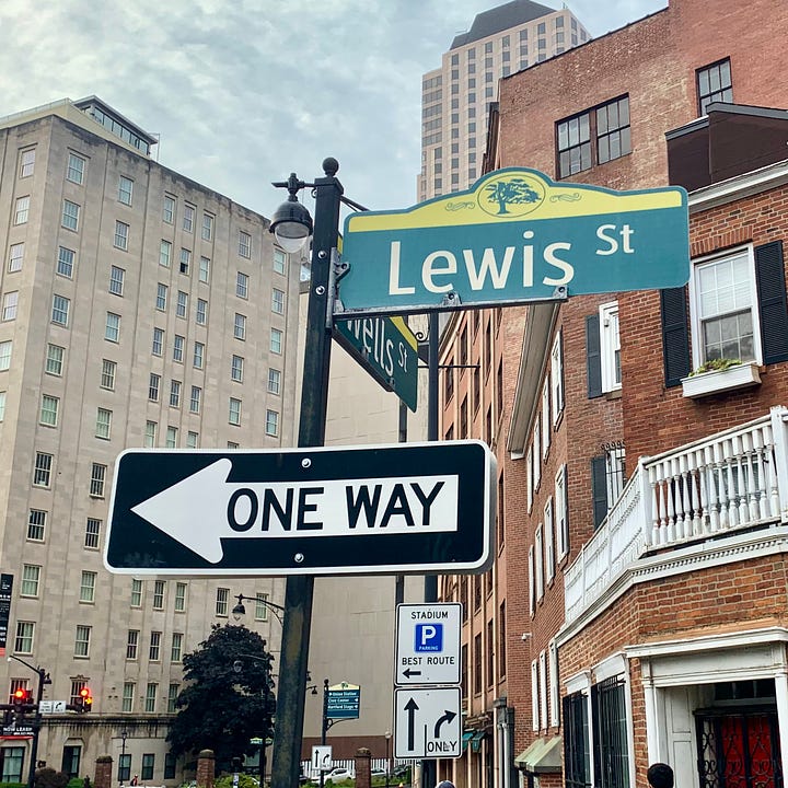 A street sign reading LEWIS and a statue of a lion