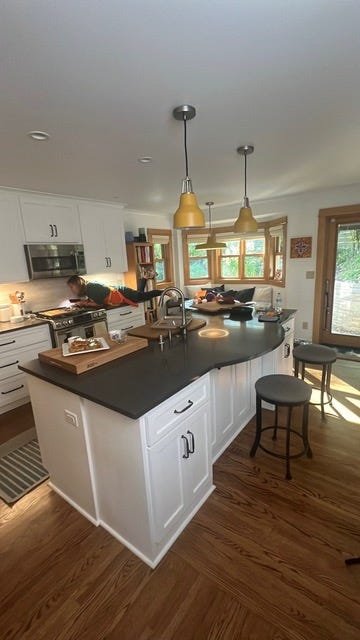 Kitchen with white walls, cupboards and dark counter tops.