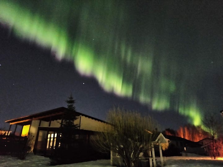 An image of green-hued Northern lights in a dark sky
