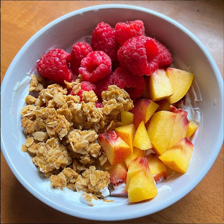 Two bowls of yogurt with various fruit and granola.