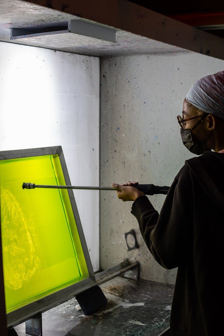 artist spraying screen for screen printing with high pressure hose mixing ink and screen printing artwork
