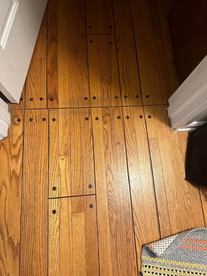 Damaged strip wood floors that are woodburned to simulate wide plank flooring with faux round peg fasteners. Also with the company's name branded into the corner.