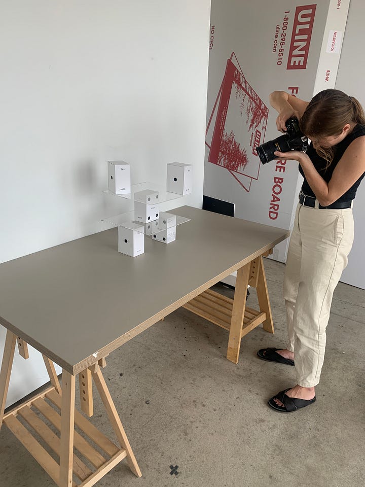 Women photographing boxes of tea on plexiglass and staged backdrops