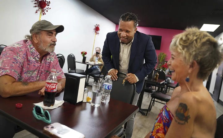 Left: Romane Pierre of Rose Goute Creole Restaurant in Springfield, Ohio, helps a line of customers, Monday, Sept. 16, 2024. Right: Karl Mattila, left, and his wife Linda, of Medway, Ohio, talk with Haitian and longtime Springfield resident Jacob Payen at Rose Goute Creole Restaurant in Springfield. Photo: Jessie Wardarski/AP, Sept. 16, 2024.