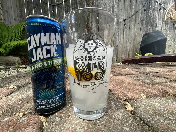 A can of Cayman Jack Margarita drink sitting next to a full pint glass on hot summery day.