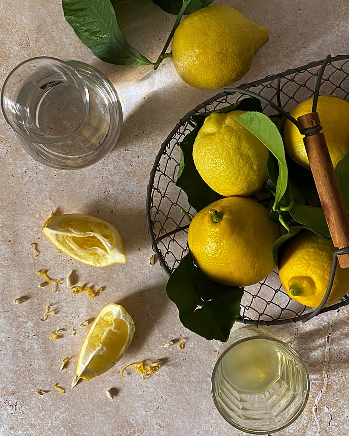 Overhead view of whole and quartered lemons on crusty white painted table