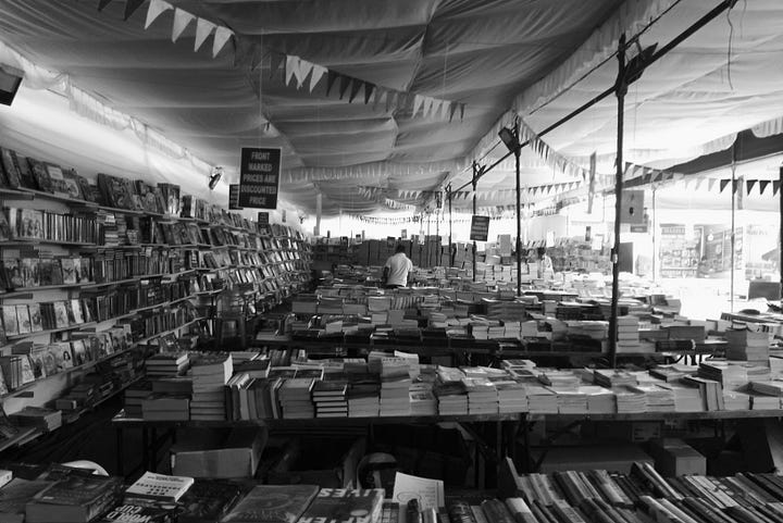 books piled up in a tent for sale and other fun fair like tents selling hand crafted products