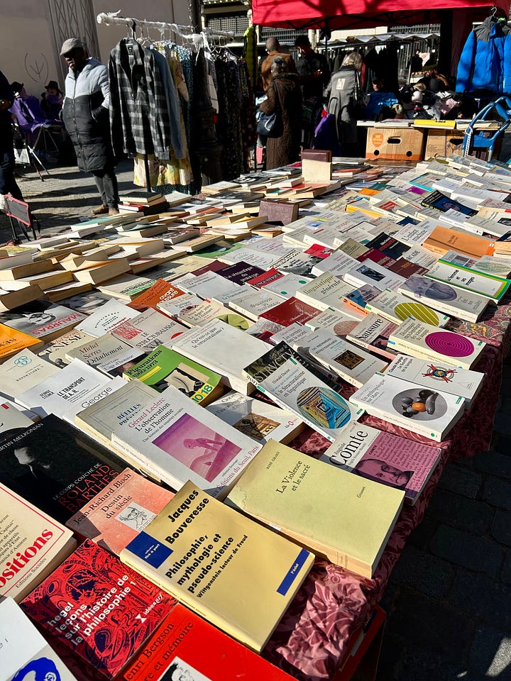 Flea market clothes, shoes, cameras, vintage tableware displayed on tables an an outdoor market