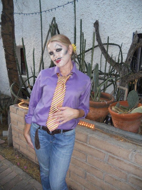 Steph in a purple button-down and tie, face painted like a skeleton, and the All Souls parade at night.