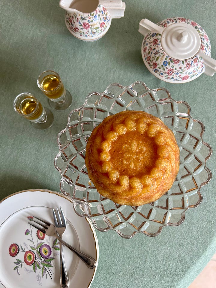 Karen holds a copper cake pan with an ornate swirl design and a fleur de lys accent. The results of the cake are displayed on a pretty table.