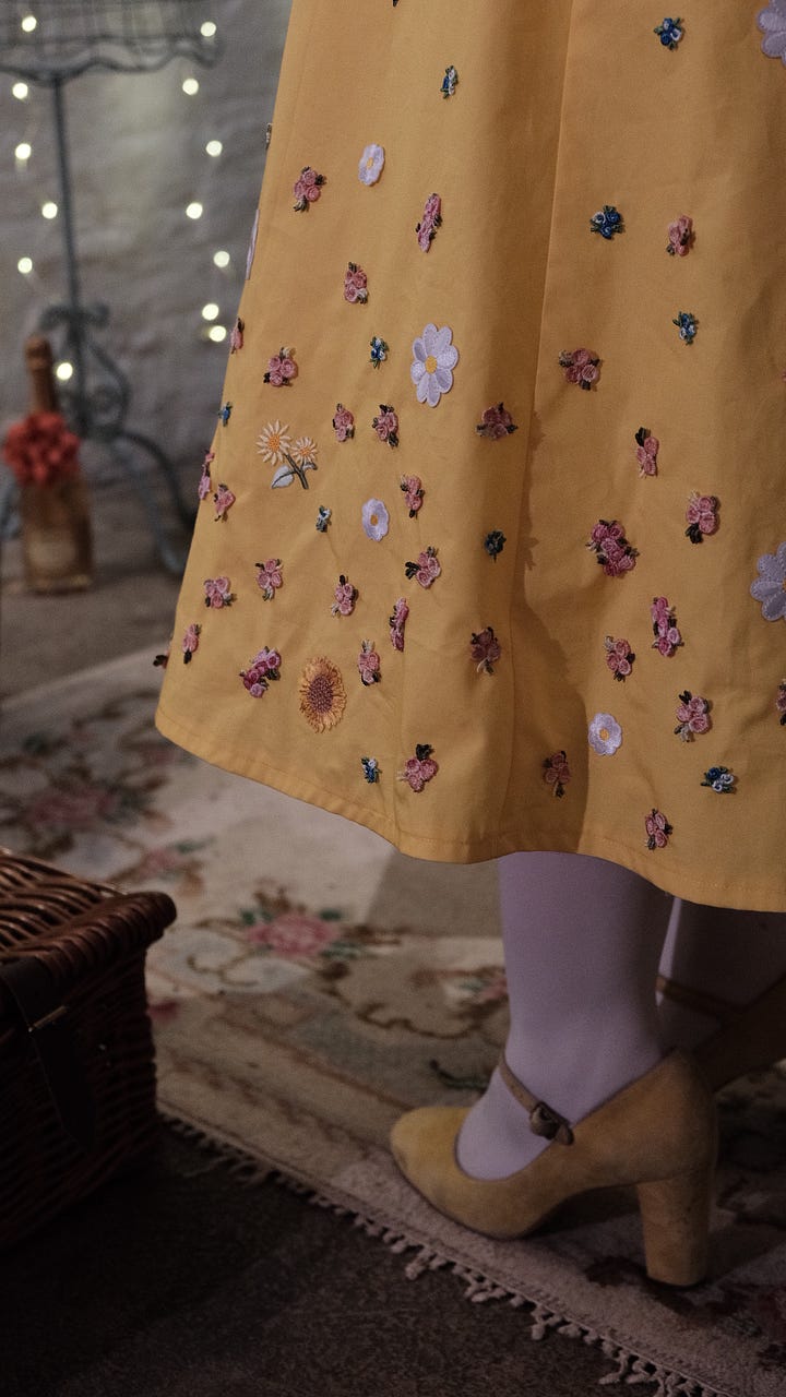 Libby wearing a vintage-style yellow dress decorated in colourful embroidered flowers