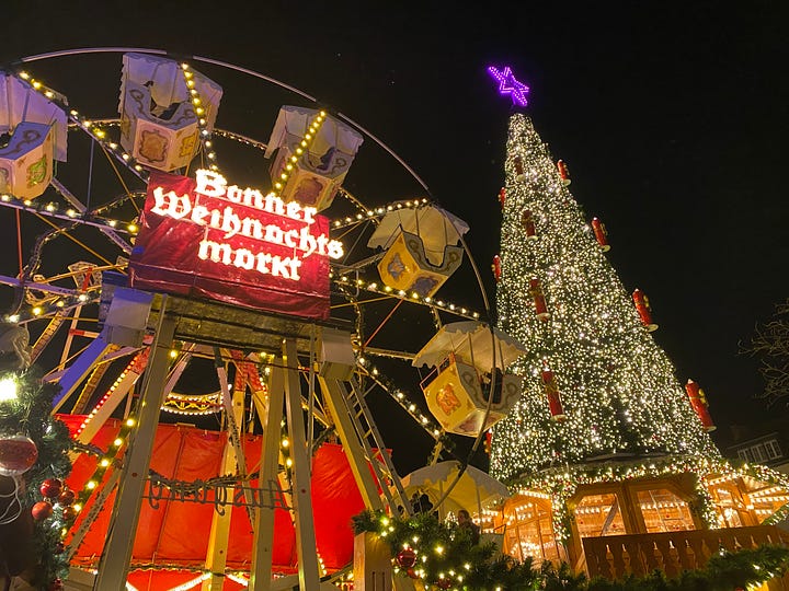 Ferris Wheel and big Christmas tree at the Christmas market in Bonn, Germany, and ten whole salmon being smoked over an open fire.