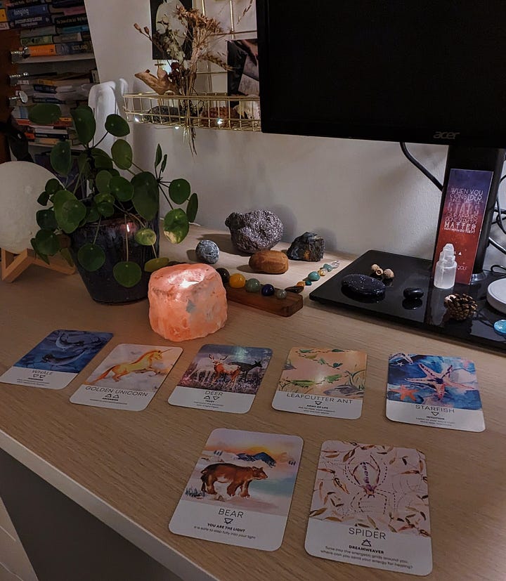 The image on the left shows six Starseed oracle cards laid out on a desk with a glowing salt candle and various crystals, the second is the same, but with seven cards from the Spirit Animal Deck