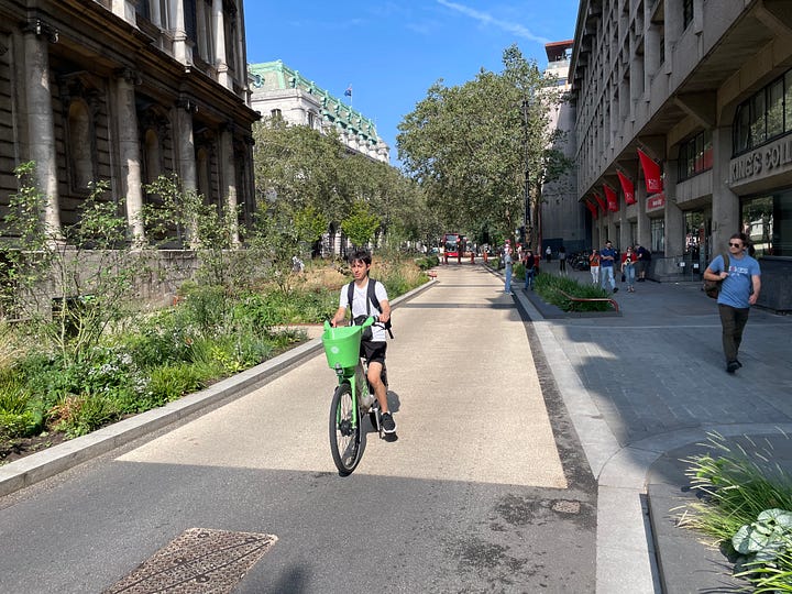 Pictures of the Strand Aldwych scheme. Many of the pictures are of pedestrian spaces, with extensive planting throughout and trees. People are walking in the street, and sitting at provided benches. There is one picture with someone on a bicycle, and another picture with my outside the disused Strand station