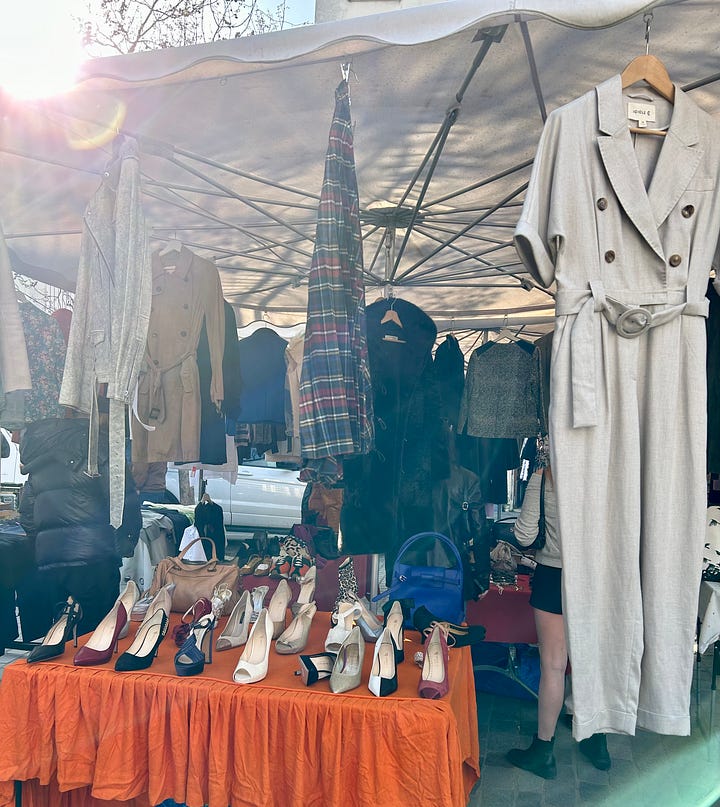 Flea market clothes, shoes, cameras, vintage tableware displayed on tables an an outdoor market
